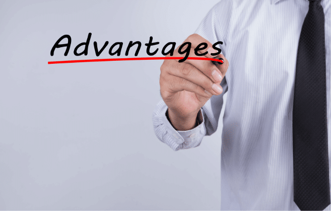 A person in business attire writing the word "Advantages" on a clear surface with a marker, with the word partially crossed out suggesting a revision or emphasis on the advantages being discussed.
