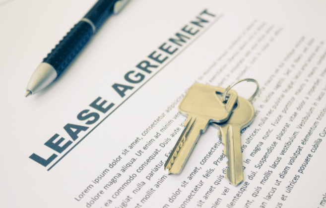 Close-up of a 'Lease Agreement' document with a pair of keys on top, indicating the signing of a rental lease.