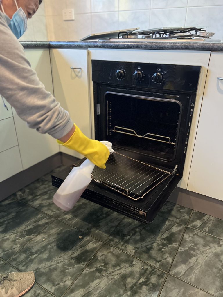 Person spraying cleaner inside an oven.
