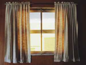 Custom DIY curtains made from old sheets hanging on a window.