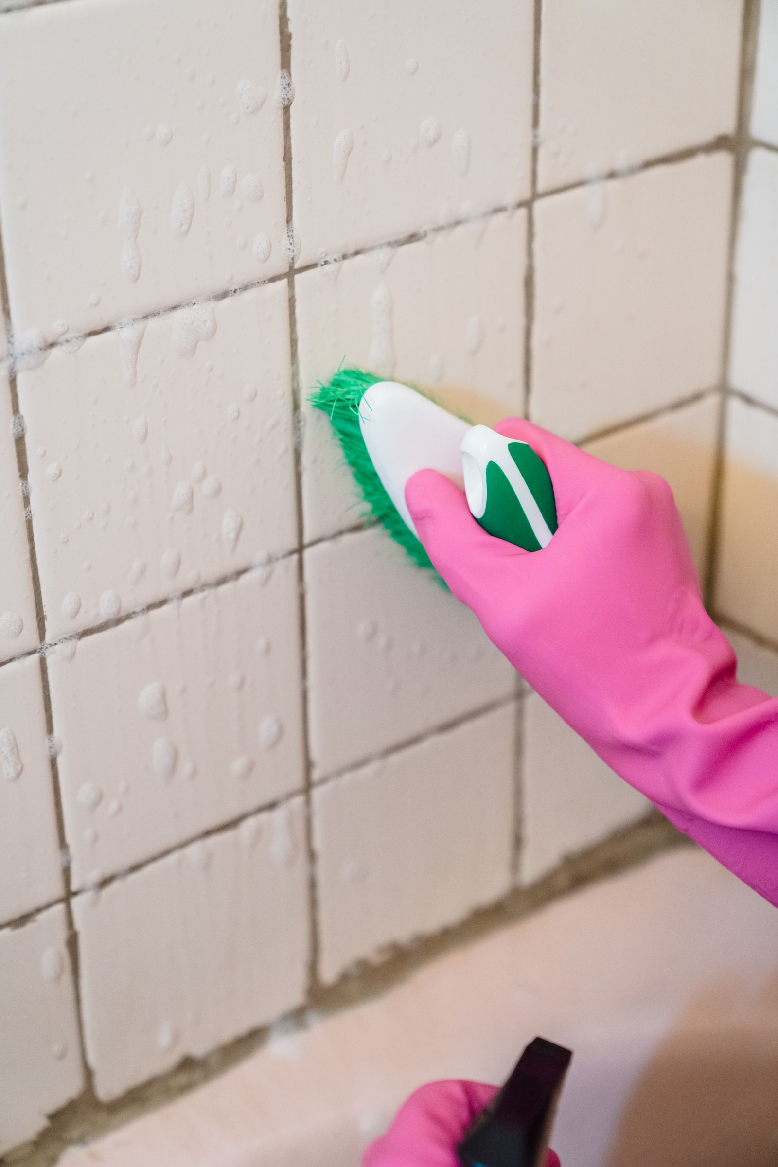 Gloved hand scrubbing bathroom tile grout during a deep clean — o2ocleaning deep cleaning Melbourne